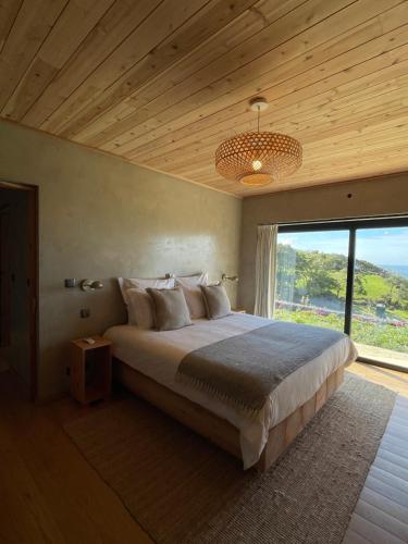 ein Schlafzimmer mit einem großen Bett und einem großen Fenster in der Unterkunft Casa da Figueira in São Roque do Pico