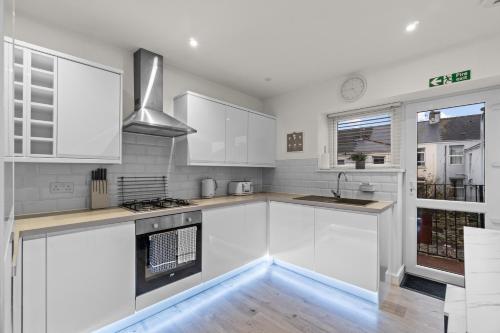 a white kitchen with white cabinets and a sink at The Grenville - Stunning Spacious Central Plymouth Apartment - Sleeps 4 in Plymouth