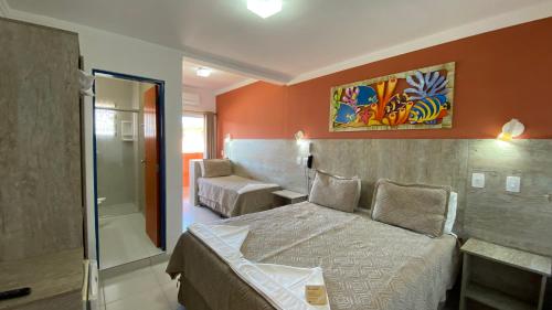 a hotel room with a bed and a bathroom at Kaliman Pousada in Ubatuba