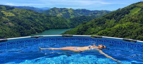 a woman laying in a swimming pool with mountains in the background at Casa Kakawa Ecolodge in Samaná
