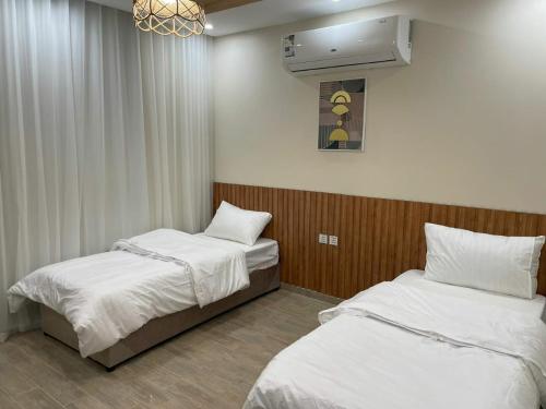 a room with two beds and a fan and a room with at شاليهات النرجس in Obhor