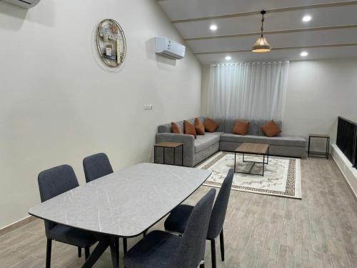 a living room with a table and a couch at شاليهات النرجس in Obhor