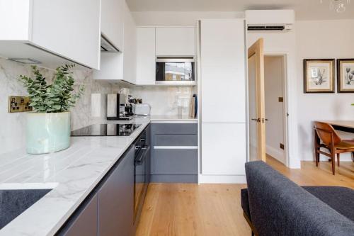 a kitchen with white cabinets and a dining room at Luxury flat on Fulham/Chelsea border in London