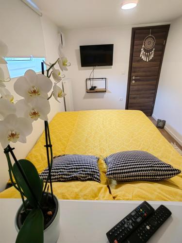 a bedroom with a yellow bed with a remote control at Home-in apartma in Ljubljana