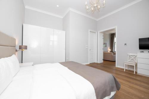 a white bedroom with a large bed and a television at Slavija Fontana Lux Apartments in Belgrade