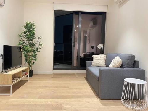 a living room with a couch and a tv at Classy 2B apt next to Albert Park w Free Parking#LA09 in Melbourne