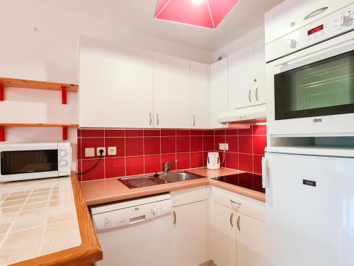 une cuisine avec des placards blancs et du carrelage rouge dans l'établissement Appartement confortable avec parking et balcon · Centre station - FR-1-425-148, à Flaine