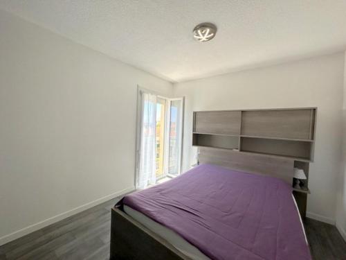 une chambre avec un grand lit avec une couverture violette dans l'établissement Agréable appartement situé au village 4B2063B, au Barcarès