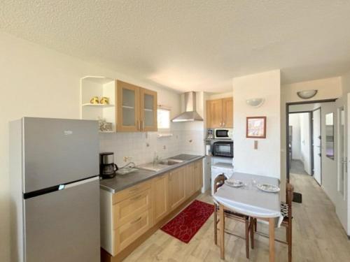une cuisine avec un réfrigérateur et une table à l'intérieur dans l'établissement Agréable appartement situé au village 4B2063B, au Barcarès