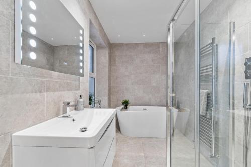 a bathroom with a white sink and a bath tub at The Grenville - Stunning Spacious Central Plymouth Apartment - Sleeps 4 in Plymouth