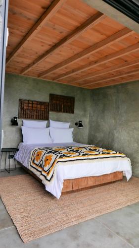 a bed in a bedroom with a wooden ceiling at Lava Homes in Santo Amaro