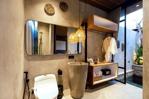 a bathroom with a toilet and a sink and a mirror at Danu Villas Bali in Kerobokan