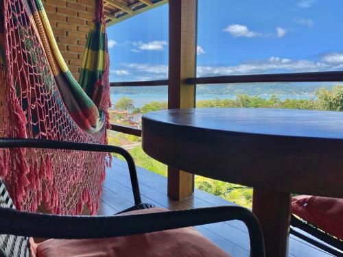 a hammock with a table and a view of the ocean at Pousada Morro do Forte in Paraty