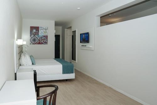 a white bedroom with a bed and a table and a chair at Carvi Beach Hotel in Lagos