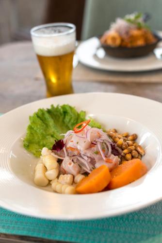 a plate of food with beans and carrots and a glass of beer at Holiday Inn - Lima Airport by IHG in Lima