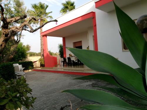 una casa con pareti rosse e bianche e un patio di Villetta Sara a Marina di Mancaversa