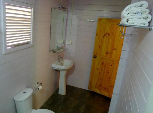 a bathroom with a toilet and a sink and a door at Mamagoa Beach Resort in Mandrem