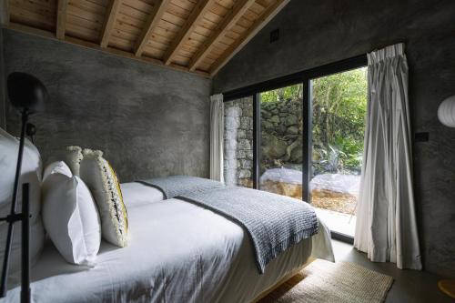 a bedroom with a bed and a large window at Lava Homes in Santo Amaro