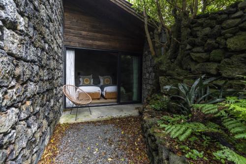 a stone house with two beds in a window at Lava Homes in Santo Amaro