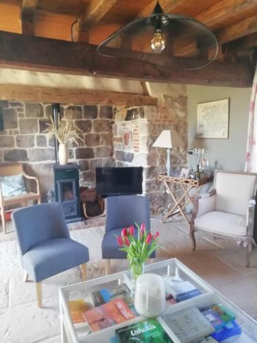 - un salon avec deux chaises et une cheminée en pierre dans l'établissement Longère entre mer et campagne, à Hubersent