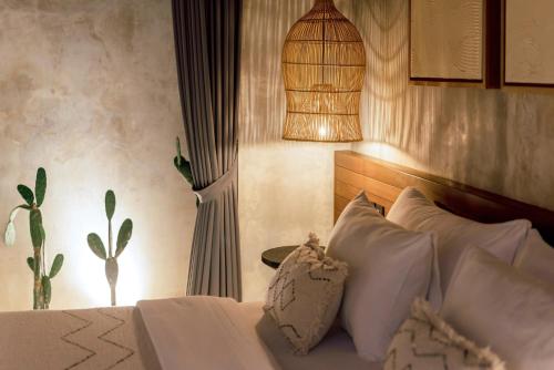 a bedroom with a bed with white pillows and a lamp at Danu Villas Bali in Kerobokan