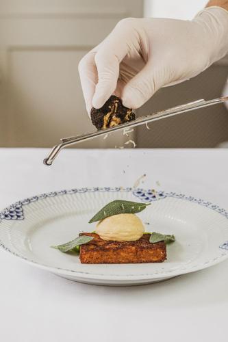 a person in gloves preparing a plate of food at Schackenborg Slotskro in Tønder