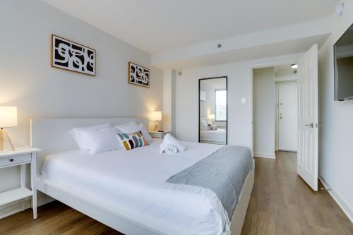 a white bedroom with a large bed and a window at Modern & Charming Apt With Rooftop @pentagon City in Arlington