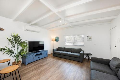 ein Wohnzimmer mit einem Sofa und einem TV in der Unterkunft Captains Retreat - Coastal Vibe in Lancelin
