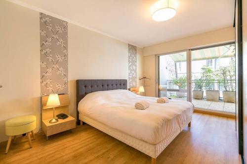 une chambre avec un grand lit et une grande fenêtre dans l'établissement Les Bambous, à Dijon