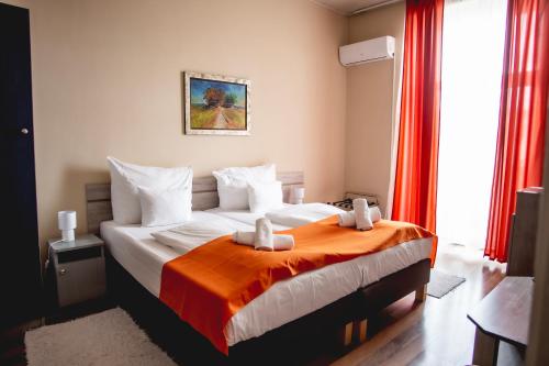 a bedroom with a large bed with an orange blanket at Hotel Kapos in Kaposvár