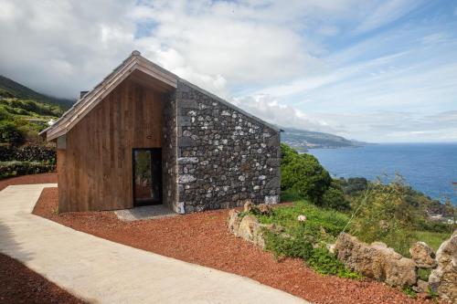 a small stone building on a hill next to the ocean at Lava Homes in Santo Amaro