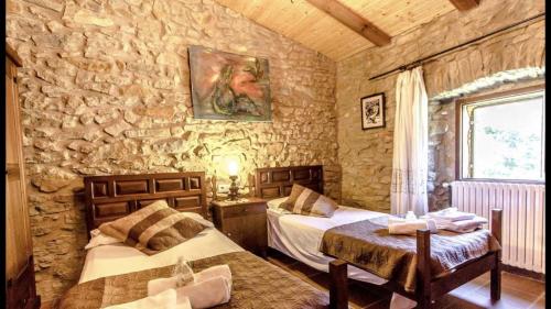 a bedroom with two beds and a stone wall at CAL CARRETER in Foixá