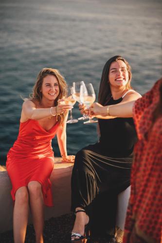 two women sitting on a ledge holding glasses of wine at 7Pines Resort Ibiza, part of Destination by Hyatt in San Jose