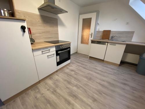 a kitchen with white cabinets and a stove top oven at Gemütliche Ferienwohnung in Stadtnähe in Oldenburg