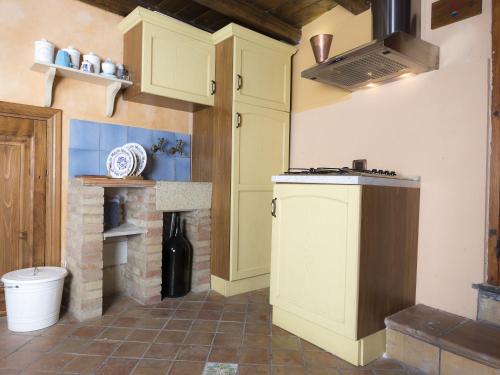 a kitchen with yellow cabinets and a brick fireplace at Antica Dimora San Girolamo in Licata