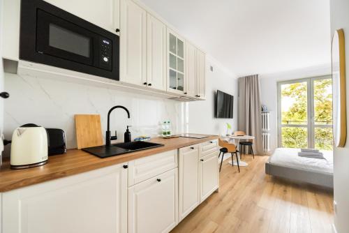 a white kitchen with a sink and a microwave at Metro Ratusz Arsenał Modern Studio in Warsaw