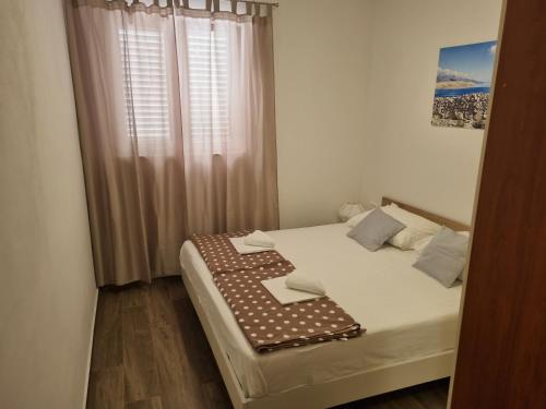 a bedroom with a bed with white sheets and a window at Apartmani Dalmatinka in Metajna