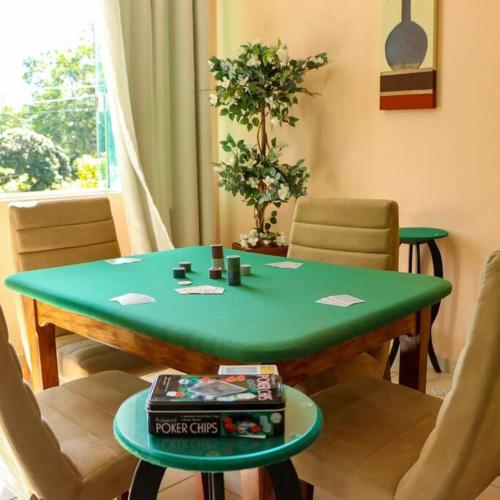 a green table in a living room with chairs at Recanto dos Beija flores, Chalé Lantana c in Monte Alegre do Sul