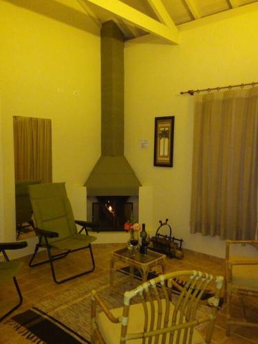 a living room with chairs and a fireplace at Recanto dos Beija flores, Chalé Lantana c in Monte Alegre do Sul