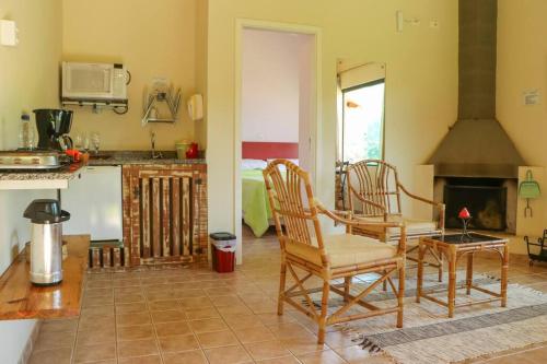 a kitchen with two chairs and a fireplace at Recanto dos Beija flores, Chalé Lantana c in Monte Alegre do Sul