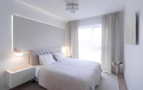 a white bedroom with a white bed and a window at 7th floor Tallinn in Iru