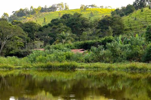 a body of water with trees and a hill in the background at Recanto dos Beija flores, Chalé Lantana c in Monte Alegre do Sul