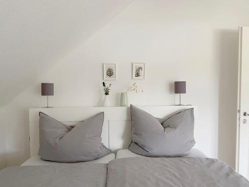 a white bedroom with two pillows on a bed at FEWO_ORTSZEIT in Haintchen
