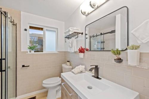 a bathroom with a sink and a toilet and a mirror at Lakeview home Walk to beach wAC fully fenced in Renton