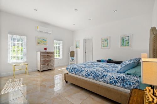 a bedroom with a bed and a dresser and windows at Modern, Stunning Bright Central Beach Villa in Nassau