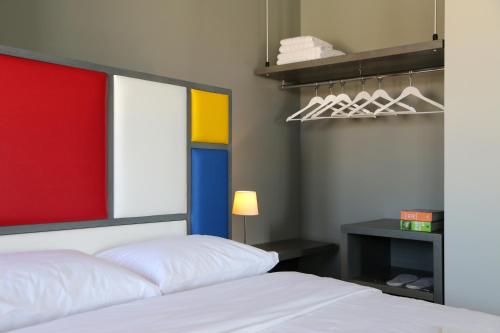 a bedroom with a white bed and a colorful window at Design Architectonika in Skiathos Town