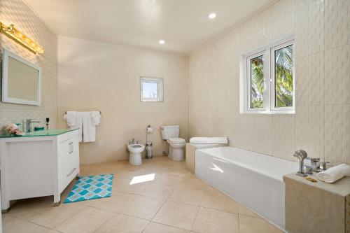 a bathroom with a tub and a toilet and a sink at Modern, Stunning Bright Central Beach Villa in Nassau