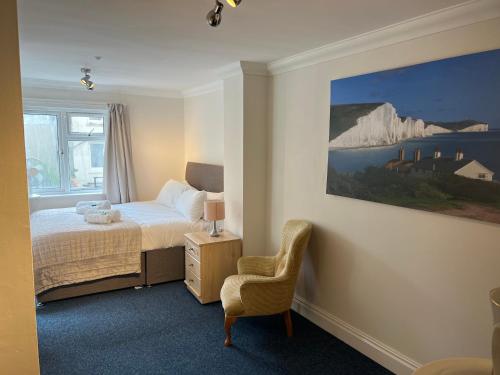 1 dormitorio con 1 cama, 1 silla y 1 pintura en One Queens Gardens, Sea View Apartment, Eastbourne., en Eastbourne