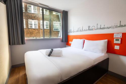 Cama en habitación con pared naranja y blanca en easyHotel Croydon en Croydon