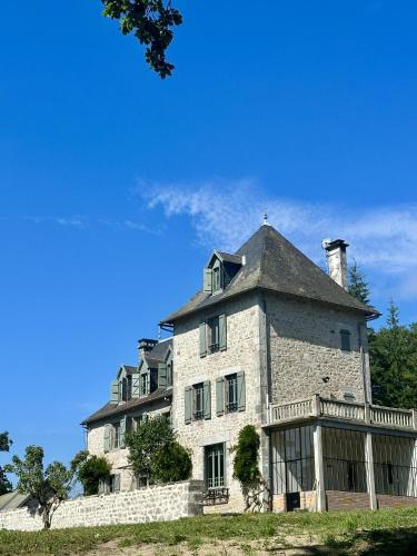 a large stone house with a roof on a hill at Le Château de Saint-Angel, Le Manoir du Rigouneix, 5 minutes A89, nature, calme, sauna in Saint-Angel